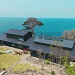 福井・ワクテラス。日本海を望む高台に建つ黒瓦の和建築を空から望む