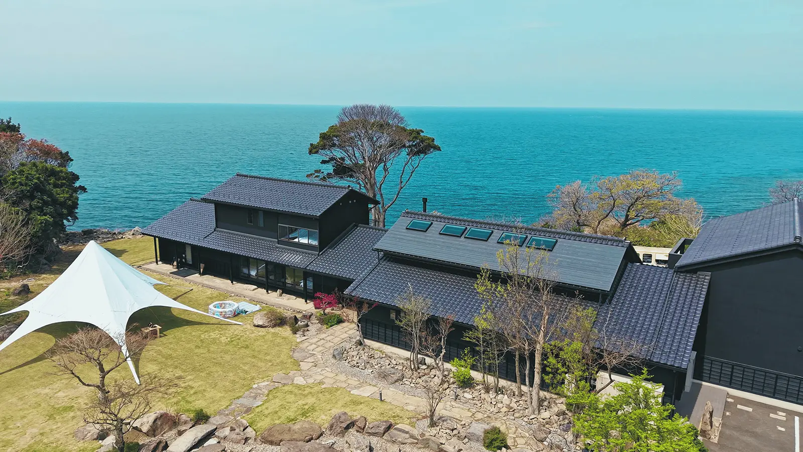 福井・ワクテラス。日本海を望む高台に建つ黒瓦の和建築を空から望む