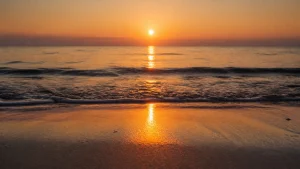 砂浜から見た、海面に一本の道のように伸びる夕日の光
